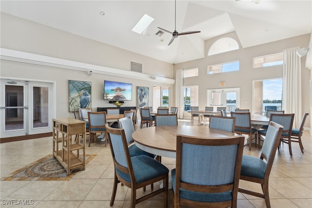 dining room with a skylight, ceiling fan, light tile patterned floors, and a high ceiling