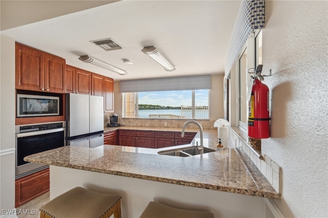 kitchen with a water view, built in microwave, a peninsula, and stainless steel oven