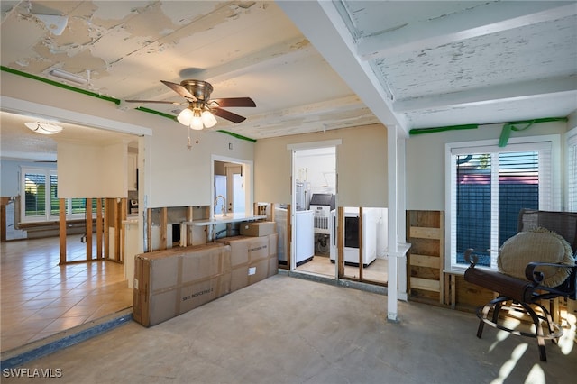 living room featuring beam ceiling, ceiling fan, sink, concrete floors, and washer / dryer