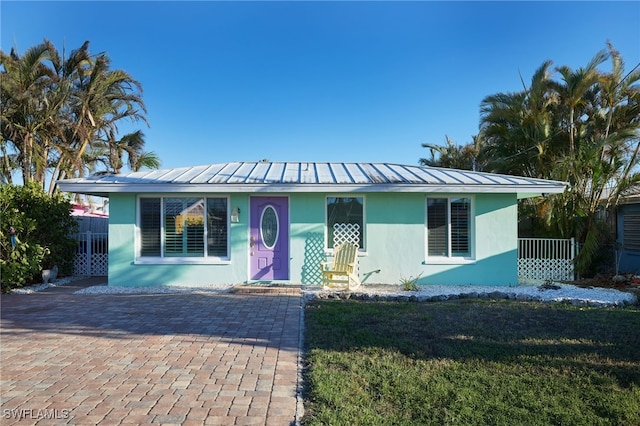 2639 Bridgeview St, Matlacha, FL 33993 - view of front of home featuring stucco siding, a front lawn, and a metal roof