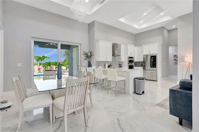 dining room with a raised ceiling, a high ceiling, and an inviting chandelier