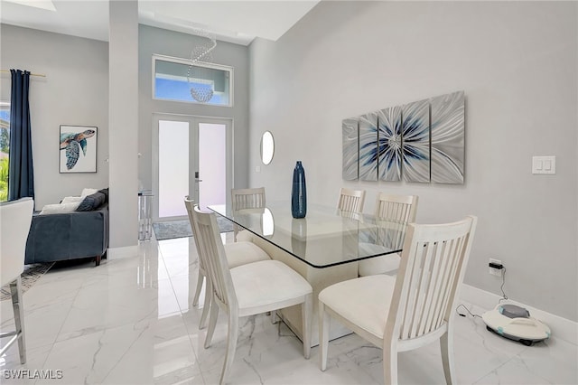 dining area featuring french doors, plenty of natural light, a high ceiling, and a notable chandelier