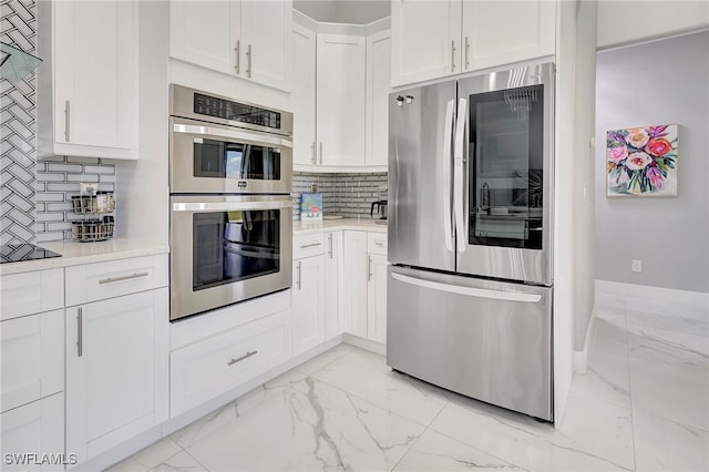 kitchen with backsplash, white cabinets, and stainless steel appliances