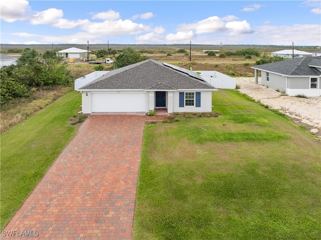 single story home featuring solar panels, a garage, and a front yard