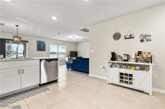 kitchen featuring white cabinets, sink, stainless steel dishwasher, decorative light fixtures, and light tile patterned flooring