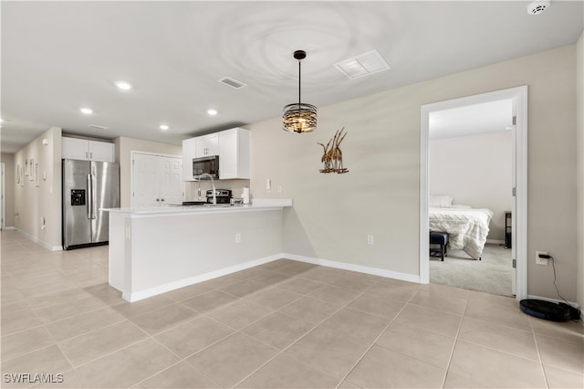 kitchen with kitchen peninsula, appliances with stainless steel finishes, light tile patterned floors, decorative light fixtures, and white cabinetry