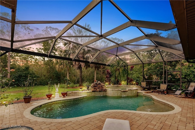 pool at dusk with a lanai, a patio area, and an in ground hot tub