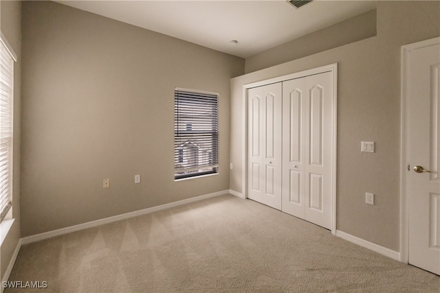 unfurnished bedroom with multiple windows, light colored carpet, and a closet