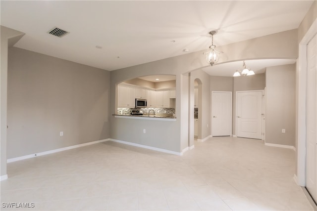 unfurnished living room with a notable chandelier and light tile patterned floors