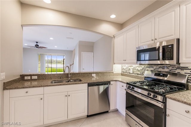 kitchen featuring white cabinetry, stainless steel appliances, dark stone countertops, sink, and kitchen peninsula