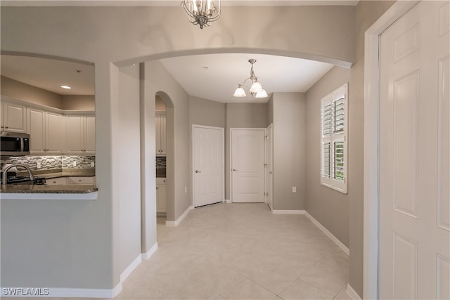 hallway featuring a notable chandelier and light tile patterned flooring