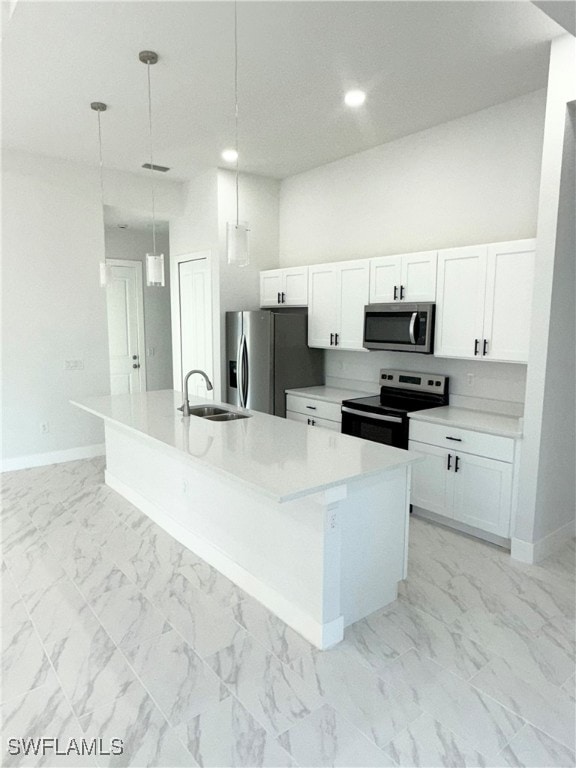 kitchen featuring white cabinets, decorative light fixtures, a center island with sink, and stainless steel appliances