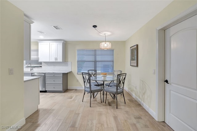 dining area featuring a chandelier, sink, and light hardwood / wood-style flooring