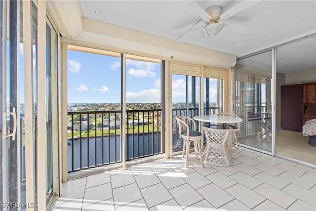 unfurnished sunroom featuring a water view, plenty of natural light, and ceiling fan