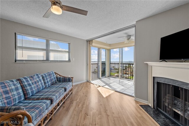 living room featuring hardwood / wood-style flooring, ceiling fan, a premium fireplace, and a textured ceiling