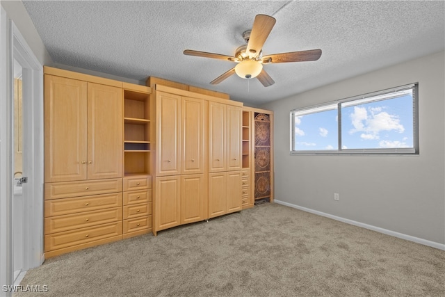 unfurnished bedroom with light carpet, ceiling fan, and a textured ceiling