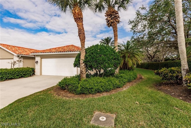 view of front of home with a tile roof, stucco siding, a front yard, a garage, and driveway