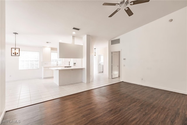 unfurnished living room featuring vaulted ceiling, ceiling fan, and light hardwood / wood-style floors