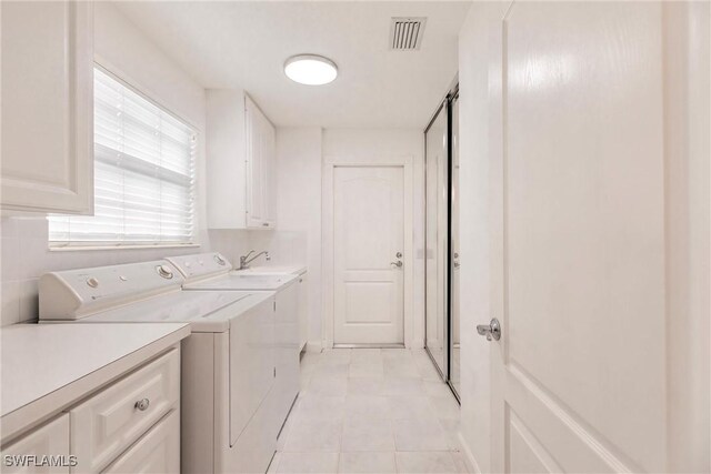 laundry room featuring independent washer and dryer, cabinets, and light tile patterned floors