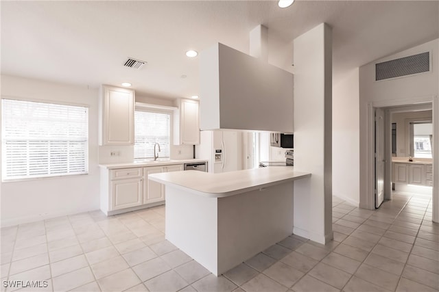 kitchen with light tile patterned flooring, sink, white cabinets, and kitchen peninsula