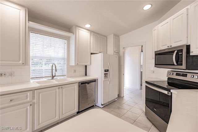 kitchen with sink, light tile patterned floors, backsplash, stainless steel appliances, and white cabinets