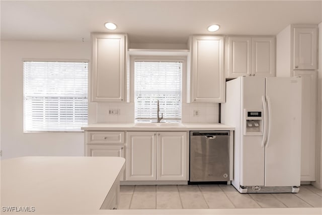 kitchen with sink, white cabinetry, white refrigerator with ice dispenser, light tile patterned flooring, and stainless steel dishwasher