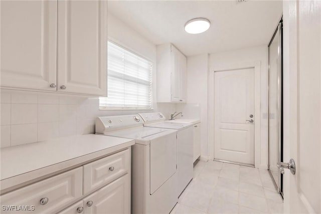 washroom featuring cabinets, washing machine and dryer, and sink