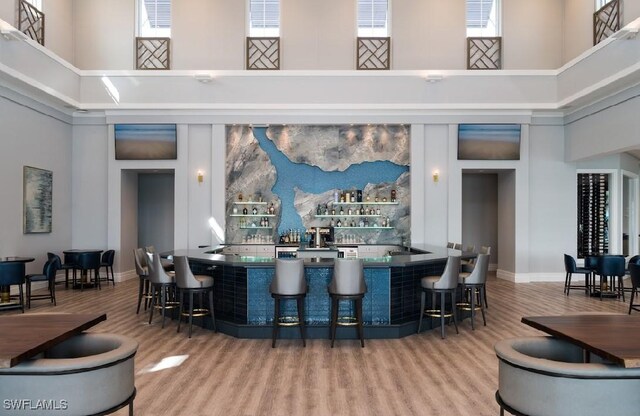 bar featuring a towering ceiling and hardwood / wood-style flooring