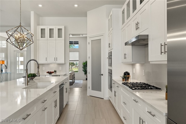 kitchen with white cabinets, pendant lighting, sink, and stainless steel appliances