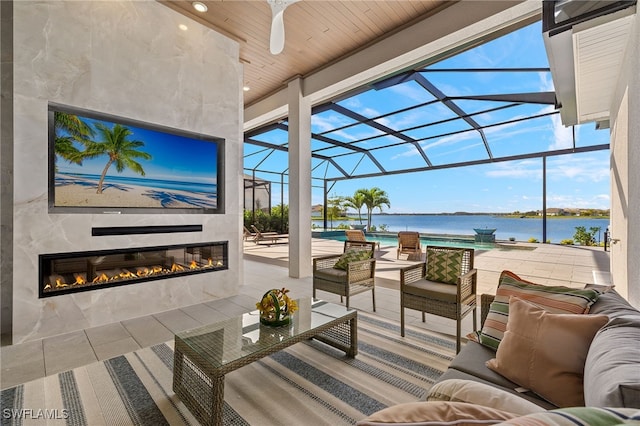 view of patio / terrace with an outdoor living space with a fireplace, a water view, ceiling fan, and a lanai