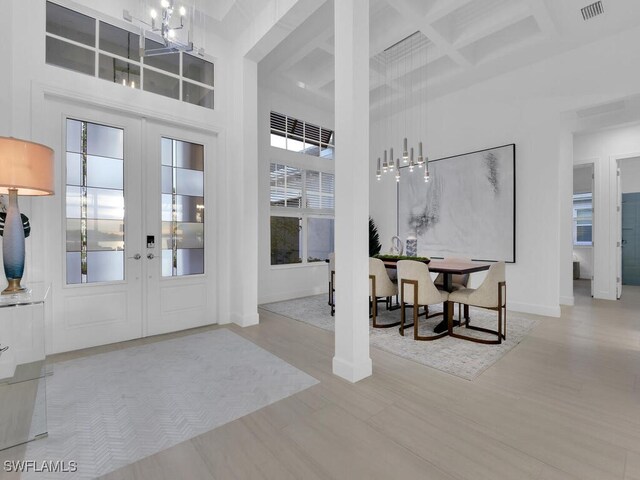 entryway with coffered ceiling, french doors, and a high ceiling