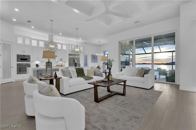 living room with light tile patterned floors, ceiling fan with notable chandelier, and sink