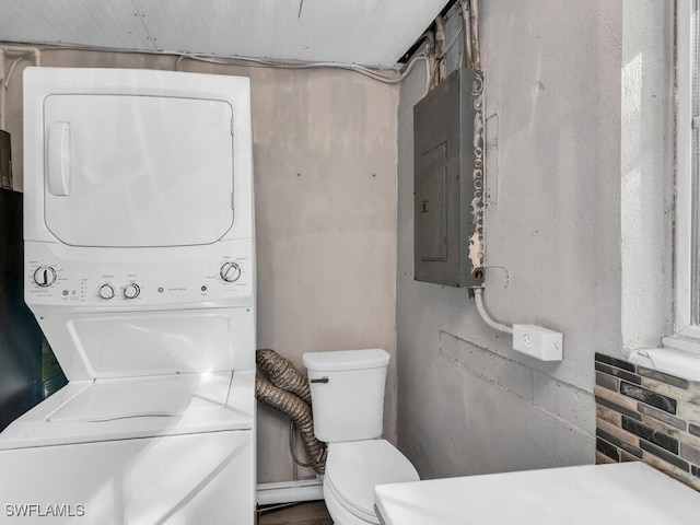 laundry room with electric panel and stacked washer and clothes dryer