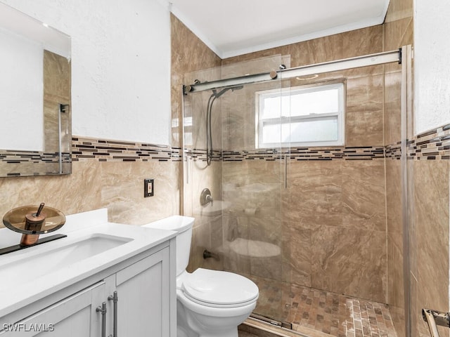 bathroom with vanity, a shower with shower door, tile walls, and toilet