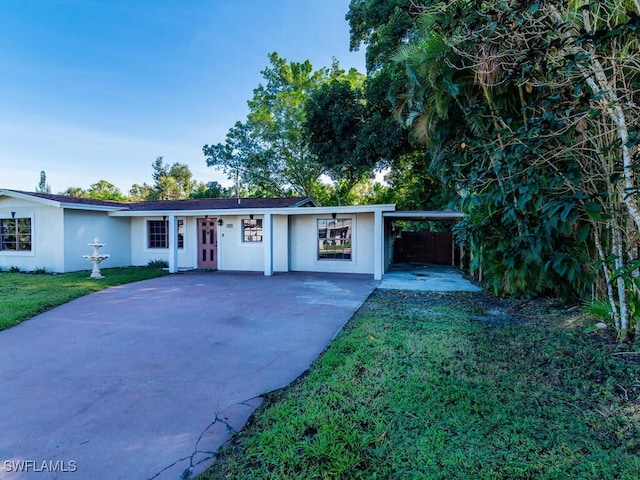 ranch-style home featuring a front lawn and a carport