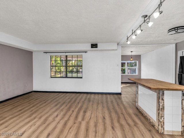 unfurnished living room with plenty of natural light, wood-type flooring, and a textured ceiling