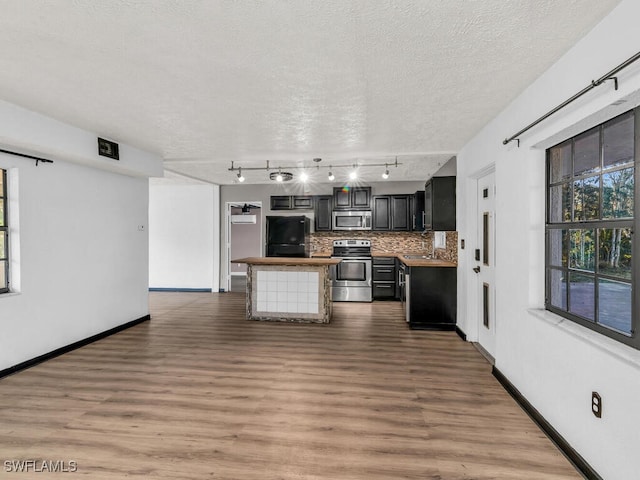 kitchen with tasteful backsplash, stainless steel appliances, a textured ceiling, and hardwood / wood-style flooring