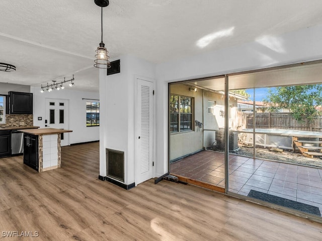 kitchen featuring butcher block countertops, tasteful backsplash, decorative light fixtures, and hardwood / wood-style flooring