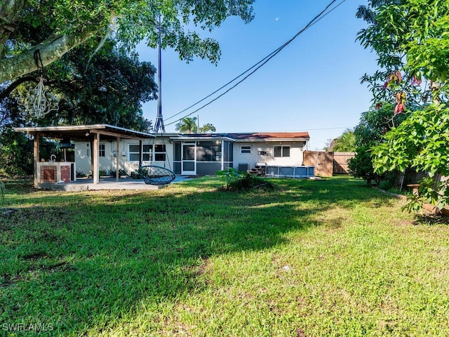 back of property with a lawn, a patio area, and a sunroom