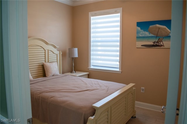 bedroom featuring light wood-type flooring, multiple windows, and crown molding