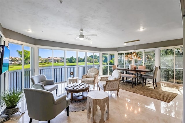 sunroom with ceiling fan and a water view