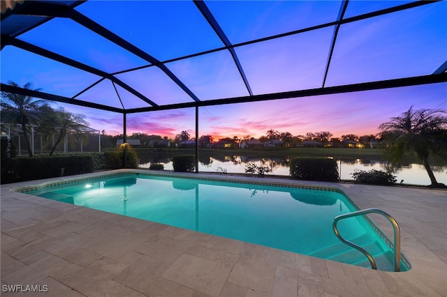 pool at dusk with a lanai, a patio area, and a water view