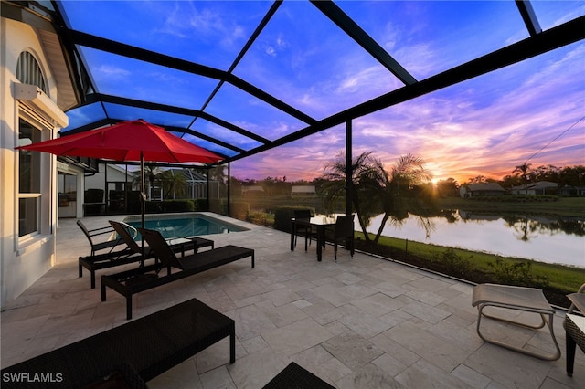 patio terrace at dusk featuring a lanai and a water view