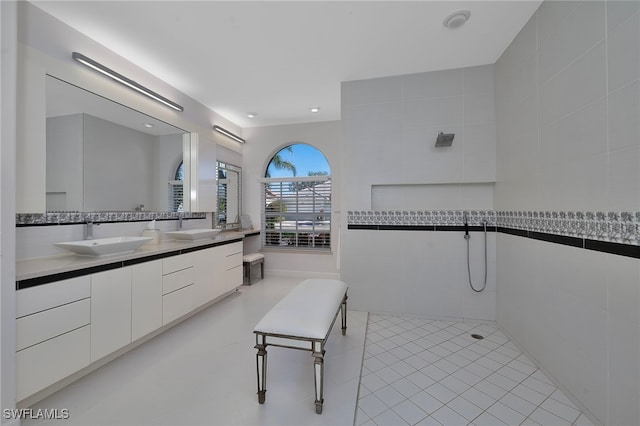 bathroom featuring tile patterned flooring, vanity, tile walls, and walk in shower