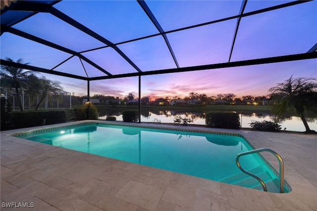 pool at dusk featuring a lanai, a water view, and a patio