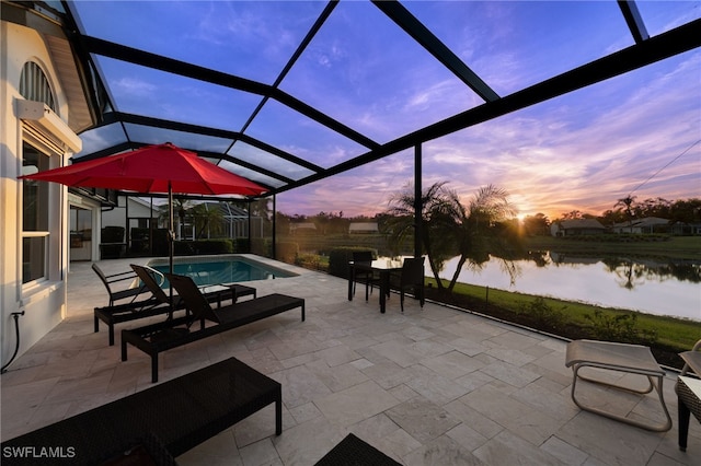 patio terrace at dusk featuring a lanai and a water view