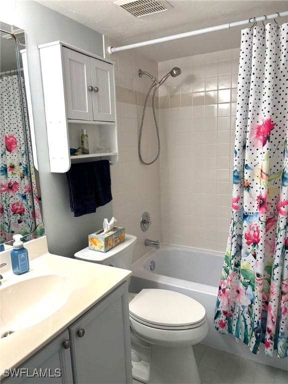 full bathroom with shower / tub combo with curtain, vanity, toilet, and tile patterned floors