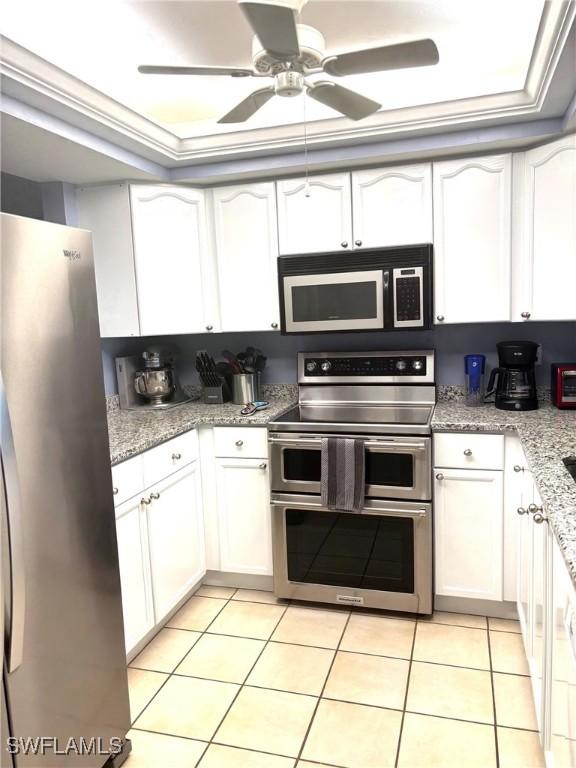 kitchen featuring appliances with stainless steel finishes, light tile patterned floors, and white cabinets