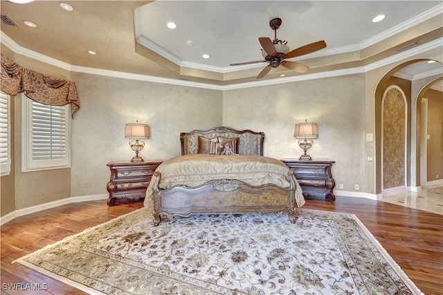 bedroom featuring wood-type flooring, a raised ceiling, ceiling fan, and crown molding