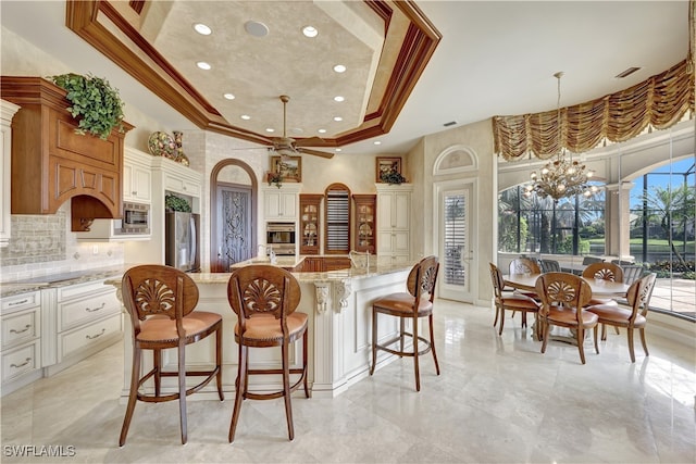 kitchen featuring light stone countertops, an island with sink, pendant lighting, and ornamental molding